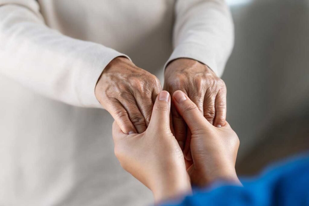 Young person holding hands of an elderly person